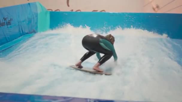 Dítě a instruktor na Flow Rider indoor surfing školení. Teenager na vodní desce školení na simulátoru vlny uvnitř. Mladý surfař během tréninku na generovaných vlnách. Vodní sporty — Stock video