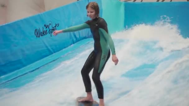Activité nautique, concept d'équilibre. Petit athlète qui aime surfer en salle. Adolescent promenades planche sur les vagues sur simulateur dans le complexe sportif. Entraîneur de surf et étudiant en session sur simulateur de vagues — Video