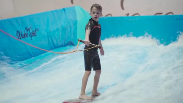 Fedett szörf sportklub gyerekeknek. Téma az aktív kikapcsolódás és extrém sport a vízen. Diák és edző szörfözik a hullám szimulátoron. Tinédzser szörfdeszka a vízi parkban — Stock videók