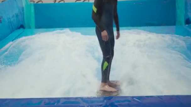 Vnitřní surfařský sportovní klub pro děti. Tématem je aktivní rekreace a extrémní sporty na vodě. Student a trenér na surfování na vlnovém simulátoru. Teenager surfing board v aquaparku — Stock video