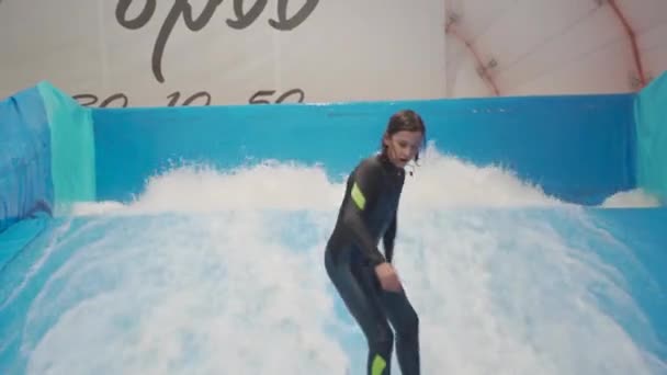 Dítě a instruktor na Flow Rider indoor surfing školení. Teenager na vodní desce školení na simulátoru vlny uvnitř. Mladý surfař během tréninku na generovaných vlnách. Vodní sporty — Stock video