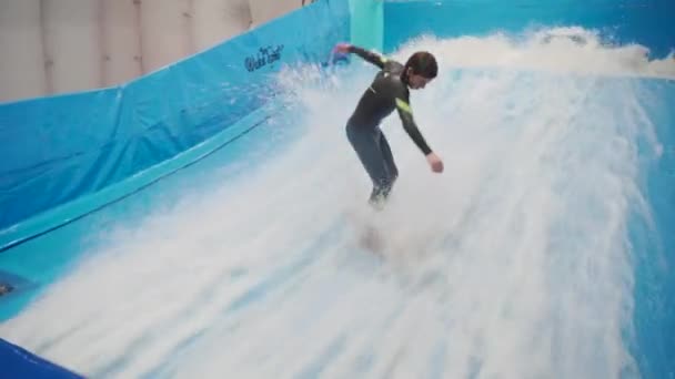 Barn och instruktör på Flow Rider inomhus surfing träningspass. Tonåring på vatten ombord utbildning på simulator våg inomhus. Ung surfare under träning på genererade vågor. Vattensporter — Stockvideo