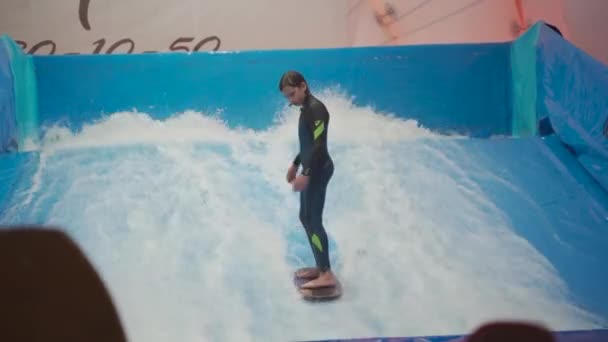 Inomhus surfing sportklubb för barn. Tema är aktiv rekreation och extrema sporter på vatten. Student och coach på surfing utbildning på våg simulator. Tonårings surfbräda på äventyrsbad — Stockvideo