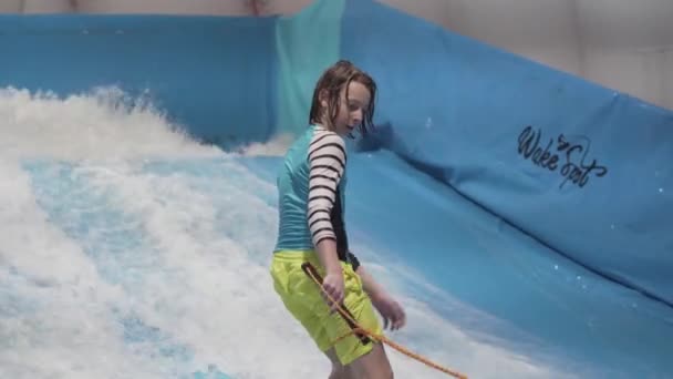 Indoor surf club sportivo per bambini. Tema è ricreazione attiva e sport estremi sull'acqua. Studente e allenatore di surf sul simulatore d'onda. Teenager surf board al parco acquatico — Video Stock