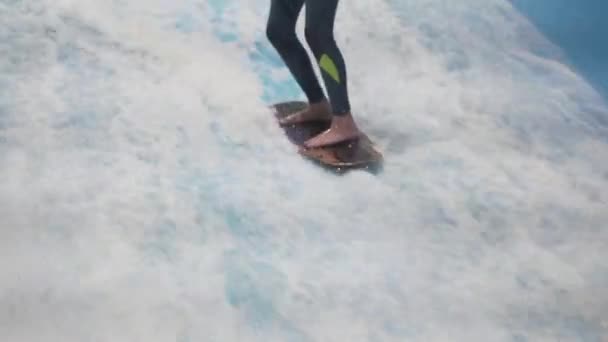 Child and instructor at Flow Rider indoor surfing training session. Teenager on water board training on simulator wave indoors. Young surfer during training on generated waves. Water sports — Stock Video