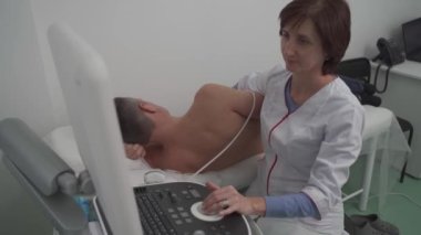 Doktor, erkek bir hastanın kalbini taramak için ultrason makinesi kullanıyor. Kardiyolog bir hastaya klinikte ekokardiyografi testi yapar. Hastanedeki hasta ultrason muayenesine alındı.
