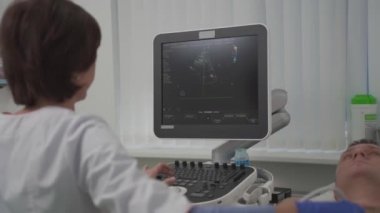 Doktor, erkek bir hastanın kalbini taramak için ultrason makinesi kullanıyor. Kardiyolog bir hastaya klinikte ekokardiyografi testi yapar. Hastanedeki hasta ultrason muayenesine alındı.