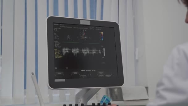 Doktorn gör en dopplersonografi på en manlig patient på en hjärtklinik. Kardiolog som gör en ultraljudsundersökning på det kardiovaskulära sjukhuset. Ekokardiografi förfarande — Stockvideo
