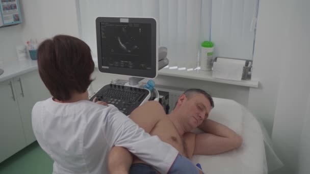 Doctor doing a doppler sonography a male patient in a cardiology clinic. Cardiologist performing an ultrasound examination at the cardiovascular hospital. Echocardiography procedure — Stock Video