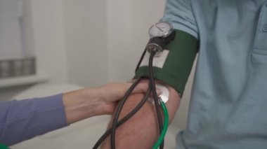 Tıbbi ve sağlık hizmetleri konsepti. Yüksek tansiyon, yüksek tansiyon ve orta yaşlı erkeklerde felç belirtileri. Sağlık kontrolü. Kadın doktor klinikteki hastaya uygulanan baskıyı ölçüyor