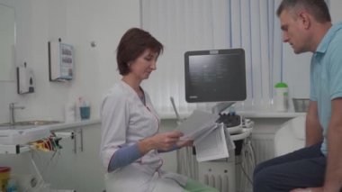 Doktor kardiyolog, modern bir klinikte sağlık kontrolü sırasında hastayla birlikte ultrason teşhisi ofisinde tıbbi testleri inceliyor. Tıbbi danışmanlık. Sağlık, Sağlık Hizmetleri