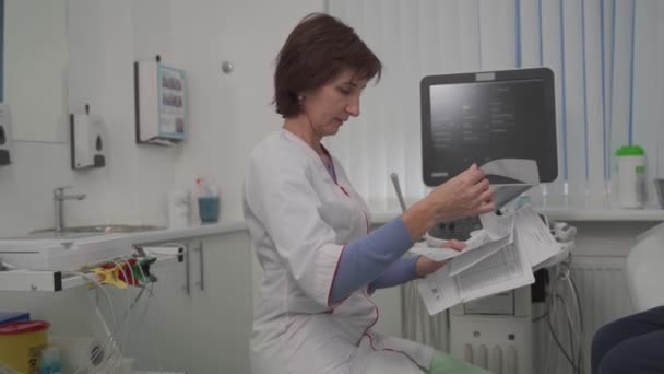 Tema de salud y medicina. Médico general femenino verá pruebas médicas durante el examen de salud del paciente masculino en el consultorio de la clínica. Trabajador médico en sala de diagnóstico por ultrasonido con paciente — Vídeo de stock