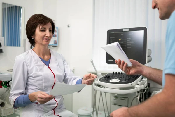 Tema della sanità e della medicina. Medico generico femminile vedrà test medici durante l'esame di salute del paziente maschile in ambulatorio. Operatore medico in sala diagnostica ad ultrasuoni con paziente — Foto Stock