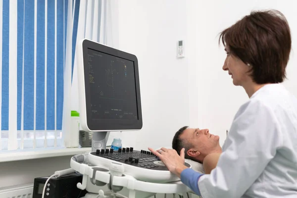 Doctor using ultrasound machine to scan heart of a male patient. Cardiologist makes a patient an echocardiographic test in a clinic. Patient under ultrasound examination in the hospital — Stock Photo, Image