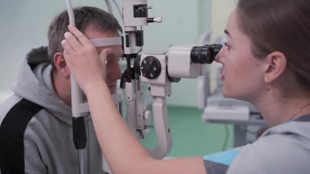 Dokter en patiënt in oogheelkundige kliniek. Mannelijke patiënt die het zicht controleert met speciale oogapparatuur. Optometrie concept. Een man die opticien bezoekt. Patiënt bij snijlamp van opticien of optometrist — Stockvideo