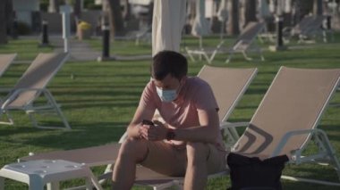 Koruyucu maskeli üzgün adam karantina ve covid 19 salgını sırasında Kıbrıs 'taki boş bir otelde dinleniyor. Salgın sırasında turizm. İyi yolculuklar. Coronavirus seyahat yasağı. Coronavirüs salgını