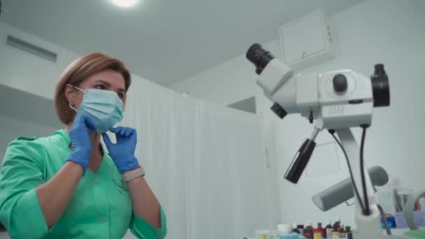 Medicine occupation career. A woman gynecologist puts on a protective mask and works with a colposcope in a modern womens health clinic. Gynecologist profession. Health feminine checkup — Wideo stockowe