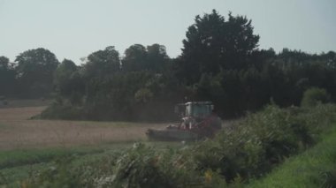 Tractor sowing crops on farm field in the north of france. Agricultural activity Brittany region, France. Tractor plowing in field. Process of growing and harvesting crops. Equipment for agriculture