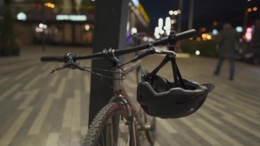 Tıbbi maskeli bir erkek bisikletçi kaskının arkasında parlayan bir ışık olan koruyucu kaskı takar ve şehirdeki otoparktan bir bisiklet alır. covid-19 konsepti için motorlu banliyö aracı