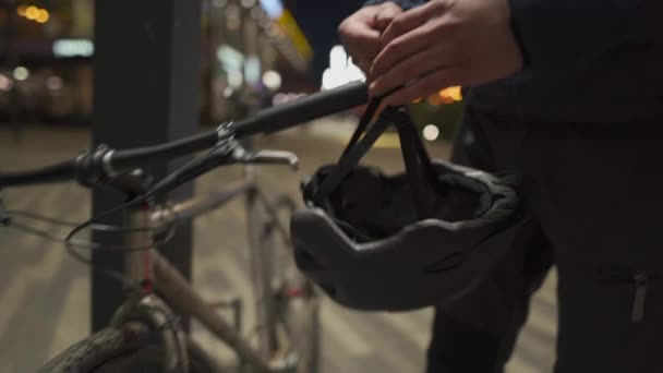 Homme cycliste dans un masque médical de protection contre la pollution de l'air, le smog, les virus, l'infection et les allergies met un casque de vélo avec lampe rouge la nuit en ville prend le vélo du parking après le travail — Video