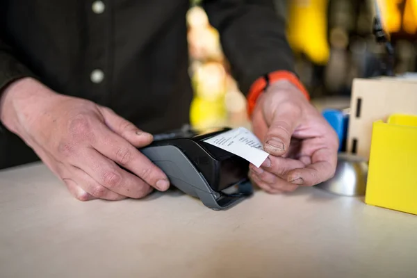 Salesmanは購入を完了するための領収書を保持しながら支払いターミナルを保持します 手を閉じて Nfc ビジネスおよび銀行取引の概念 紙テープで決済端末 銀行ターミナル — ストック写真