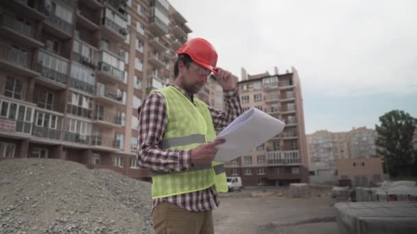 Inovativní dohlížitel ve stavebnictví v přilbě a nositel kontroluje materiály a množství porovnává s doklady na staveništi obytné budovy. Stavební inspektor při práci — Stock video