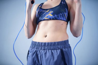 Gülen sporcu kadın ip atlarken poz veriyor. İple poz veren kaslı vücutlu bir kadın. Fitness modeli. Vücut pozitifliği, spor, fitness konsepti. Sağlıklı bir yaşam tarzı. İple atlayan zinde bir kadın..