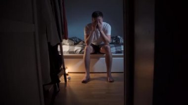 Bir adam gece baş ağrısı ile uyandı ve su içti, geceleri yatakta otururken elleriyle başını tuttu. Uykuya dalmaya çalışırken ağrı. Partiden sonra akşamdan kalma ya da grip. Yatma zamanı.