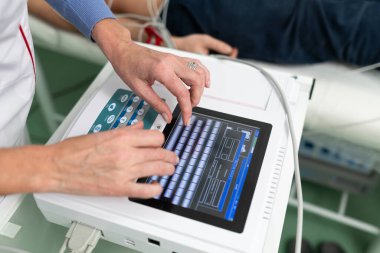 Elektrokardiyogram için tıbbi ekipman. Erkek hastaya EKG testi yapan doktorlar. Kalp krizi teşhisi, taşikardi. Elektrokardiyografi prosedürü. Kardiyolog kontrol testi yapıyor..