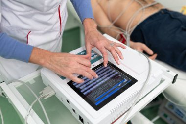 EKG konsepti. Kadın kardiyolog, kardiyoloji kliniğindeki hastaya elektrokardiyogram testi yapıyor. Tıp, kardiyoloji, kalp konseptinin EKG 'si. Tıbbi testlerde erkek..