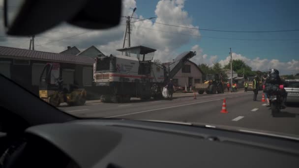 Ukraina, Kiev. Vägen till Vyshgorod genom byn Novye Petrovtsy den 20 maj 2021. Reparation av vägar, traktorer och arbetstagare som flyttar bilar genom vindrutan och en trafikstockning från bilar — Stockvideo
