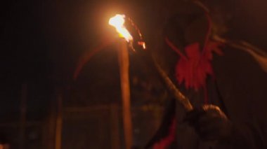 Ölüm kostümü giymiş, tırpanlı bir adam Cadılar Bayramı 'nda elinde meşale tutuyor. Ölüm Meleği, Ölüm. Korku ve Hayalet kavramı. Cadılar Bayramı ve korkunç sahne teması. Geceleri yanan meşale