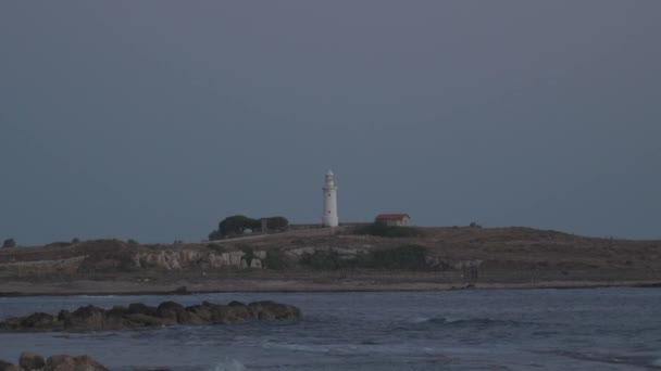 Fehér ősi világítótorony a Földközi-tengeren a város paphos szigetén cifra kilátás nyílik a tengerre és a strandra. Utazz át a Földközi-tenger városain. Hétvége Ciprus szigetén — Stock videók