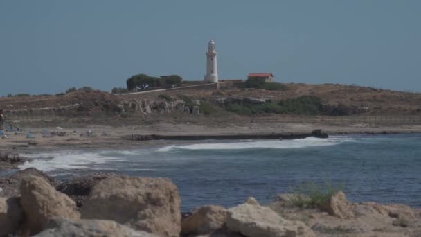 Белый древний маяк на Средиземном море в городе Пафосе на острове Кипр с видом на море и пляж. Путешествие по городам Средиземноморья. Выходные на острове Кипр — стоковое видео