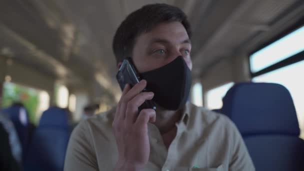 Homem mascarado a ligar para alguém no comboio no novo normal. Homem em máscara médica falando no smartphone enquanto vai trabalhar de trem. Comunicação durante o COVID-19 no metrô — Vídeo de Stock