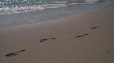 Okyanusun yakınındaki kumlu sahilde ayak izi. Güneşli havalarda, Akdeniz kıyısındaki sahilde ayak izleri. Kumda izler var. Kumsalda ayak izleri