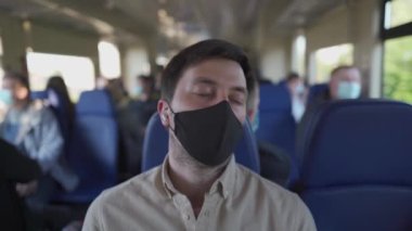 Kulaklıklı, koruyucu maskeli ve metroda dinlenen gözleri kapalı bir erkek yolcu. Tren uykusunda kablosuz kulaklıkla müzik dinleyen yorgun maskeli adam. Seyahat ederken podcastlar