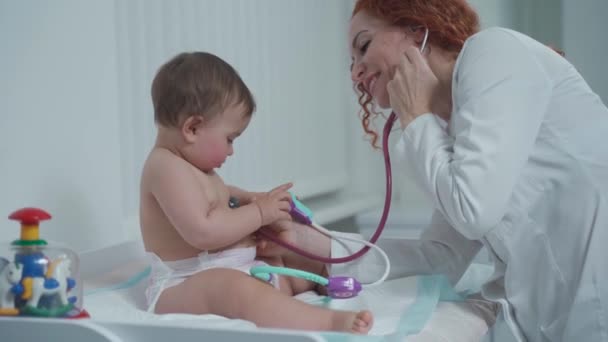 Pediatra que brinda atención médica a su paciente bebé en el consultorio de una clínica especializada para niños. Neonatólogo. Cita médica niño pequeño de un año en la clínica. Asistencia sanitaria de — Vídeos de Stock