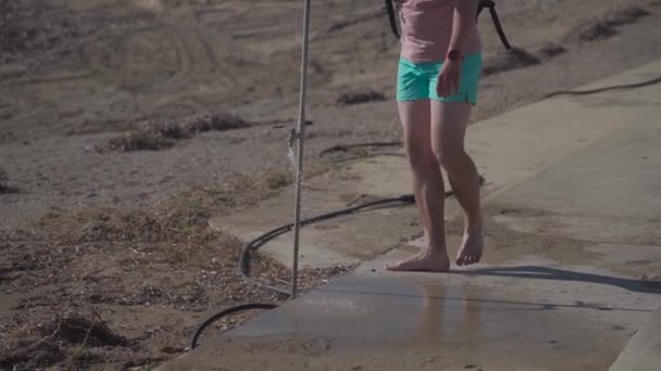 Uomo caucasico lava i piedi sotto la doccia in spiaggia, lava i piedi dalla sabbia con acqua di rubinetto vicino alla spiaggia di Paphos, Cipro — Video Stock