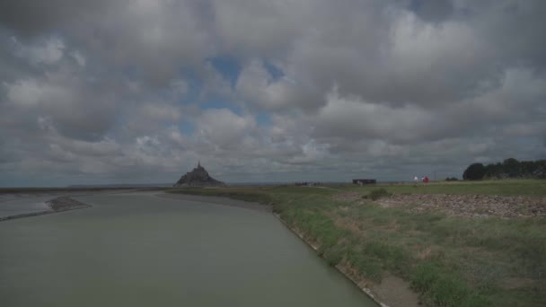 Rzeka Cuenon i droga z pieszymi turystami do zamku opactwa Mont Saint-Michel w regionie Normandii północnej Francji — Wideo stockowe