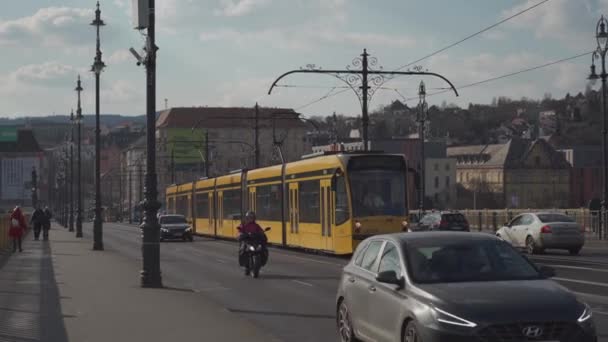 8 марта 2022 Будапешт, Венгрия. Общественный транспорт Будапешта. Желтый трамвай мчится по рельсам через старый город в Будапеште — стоковое видео