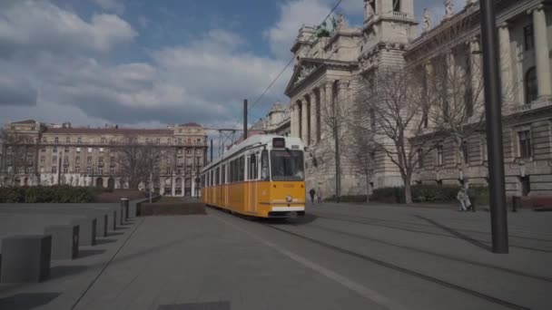 8. maaliskuuta 2022 Budapest, Unkari. Julkinen liikenne Budapestissa. Tyypillisiä keltainen raitiovaunu kulkee kiskot läpi vanhan kaupungin Budapest — kuvapankkivideo