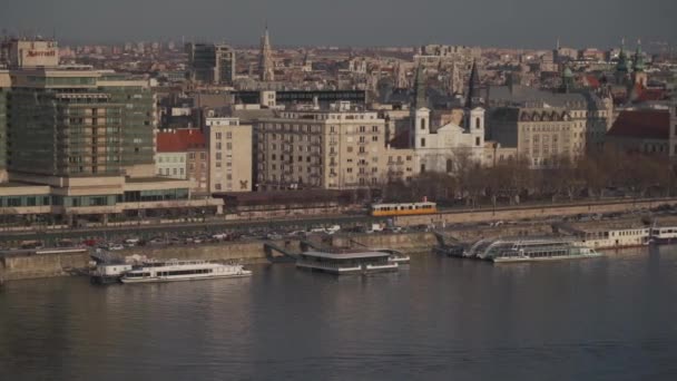 2022年3月8日、ハンガリー、ブダペスト。テーマはブダペストの公共交通機関と列車システムです。典型的な黄色の街の路面電車は、晴れた春の天気でブダペストのメインストリートを通過します — ストック動画