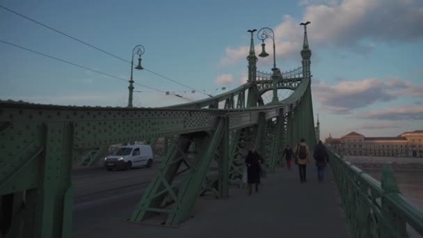 8. března2022. Budapešť. Maďarsko. Ancient Green Bridge, Liberty Bridge s dopravou a procházející chodci v Budapešti při západu slunce — Stock video