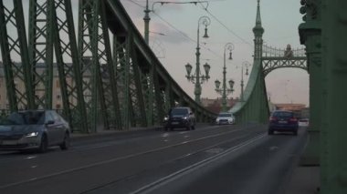8 Mart 2022. Budapeşte. Macaristan. Budapeşte 'nin ünlü yeşil metal özgürlük köprüsü Tuna Nehri' ni geçiyor. Gün batımında geçen arabalar ve yayalarla birlikte. Szabadsag saklandı. Buda ve Haşere 