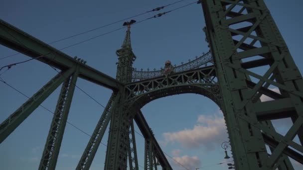 8 марта 2022 года. Будапешт. Венгрия. Известный зеленый металлический мост через Дунай на закате вечером с проезжающими автомобилями и пешеходами — стоковое видео