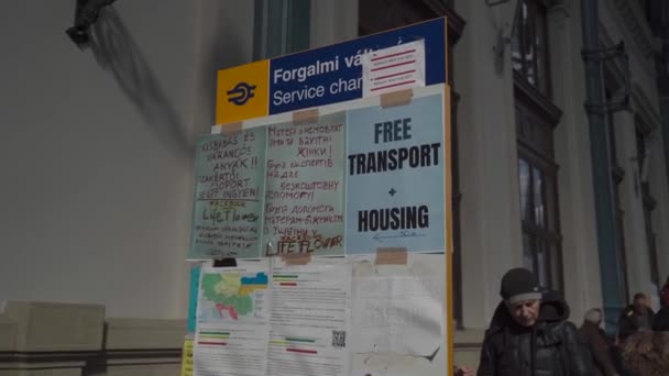 BUDAPESHT, Hongarije, 8 maart 2022, Message Board for Refugees from the War in Ukraine arriveert op het treinstation, waar ze worden begroet door hulpverleners die voedsel en voorraden uitdelen.. — Stockvideo