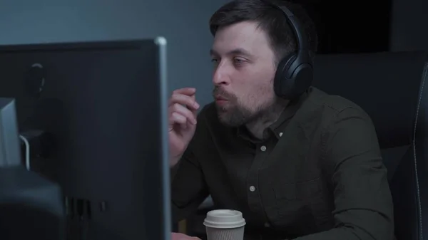 Blanke man in headset kijk naar laptop scherm werk online vanuit kantoor. Jonge man in hoofdtelefoon kijken webinar cursus of training op het web op de computer. Afstandsonderwijs concept, videogesprek — Stockfoto