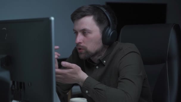 Skupiony mężczyzna noszący słuchawki, trzymający wideo rozmowy z klientami przy komputerze. Skoncentrowany męski wykład w klasie edukacji online doradzający klientom z laptopem w domu. Aplikacja wideokonferencyjna — Wideo stockowe