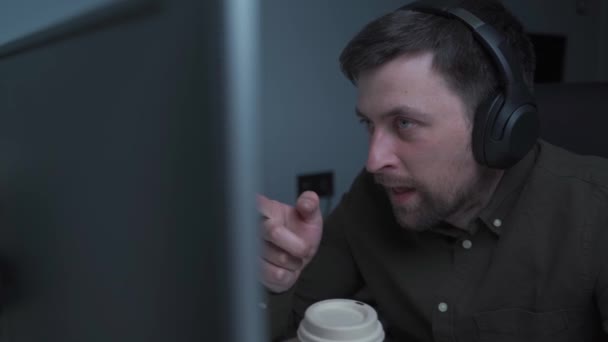 Soustředěný muž ve sluchátkách, drží videohovor s klienty u počítače. Soustředěné mužské přednášky v on-line vzdělávání poradenství klientům s notebookem doma. Videokonferenční aplikace — Stock video